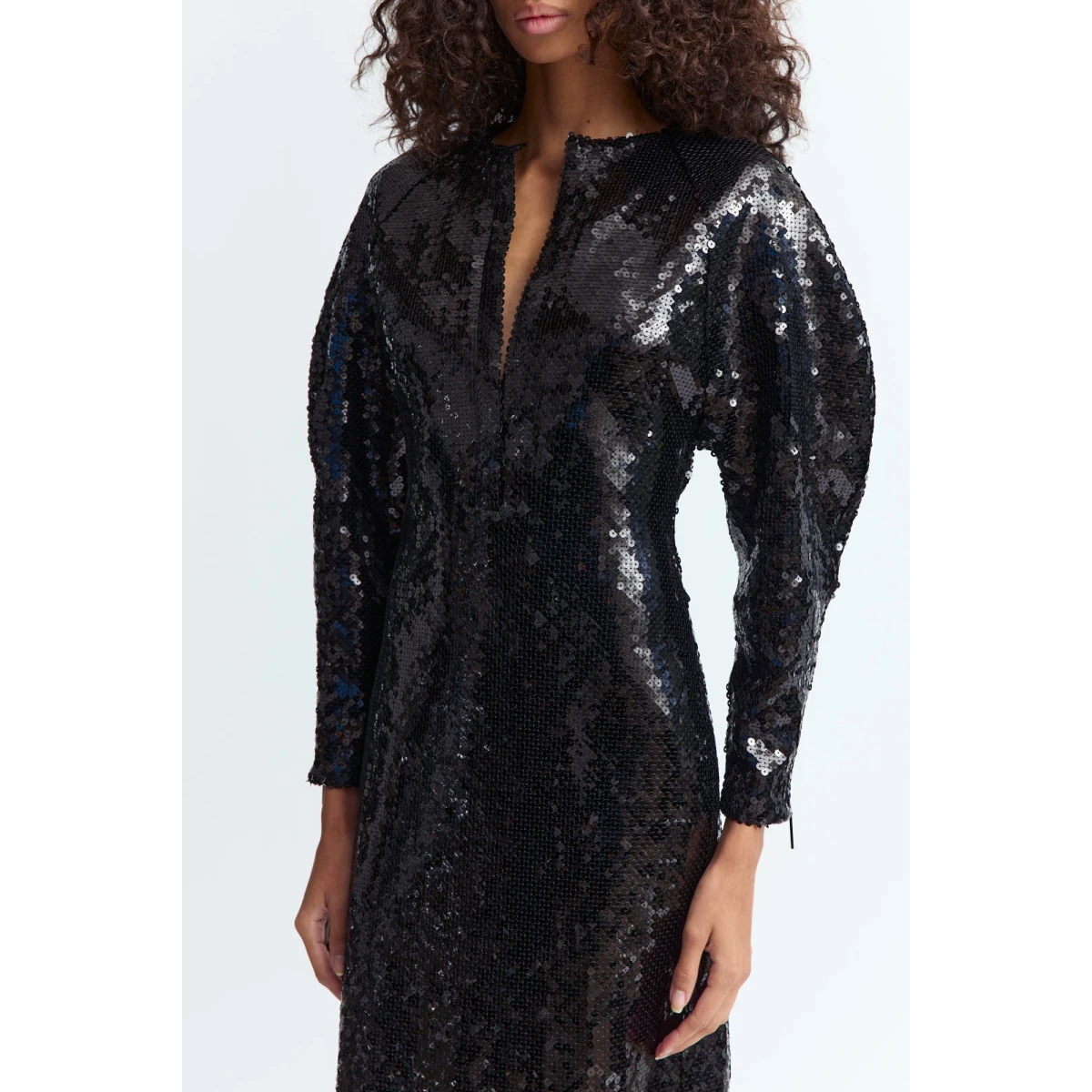 liquid shine. It features a slim plunge split at the front and sculptural long sleeves; voluminous through the shoulders and upper arms before tapering at the wrists. Designed to skim the body