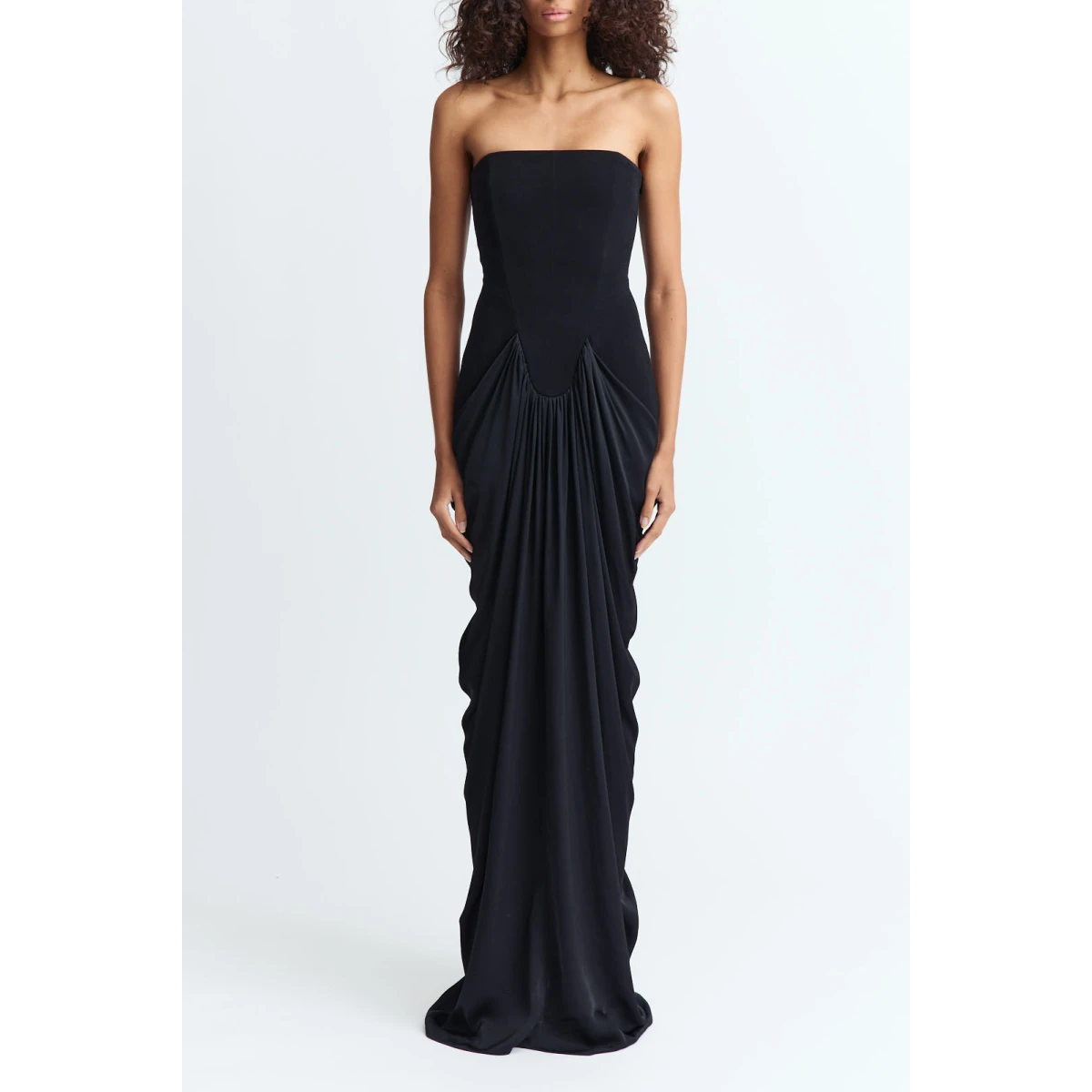 fitted gown designed to contour the body. It features dramatic pleated draping that sweeps across both the front and back