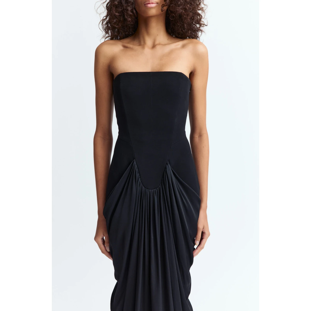 creating depth and fluidity through the otherwise minimal shape. The floor length cut extends the form with clean