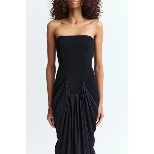 creating depth and fluidity through the otherwise minimal shape. The floor length cut extends the form with clean