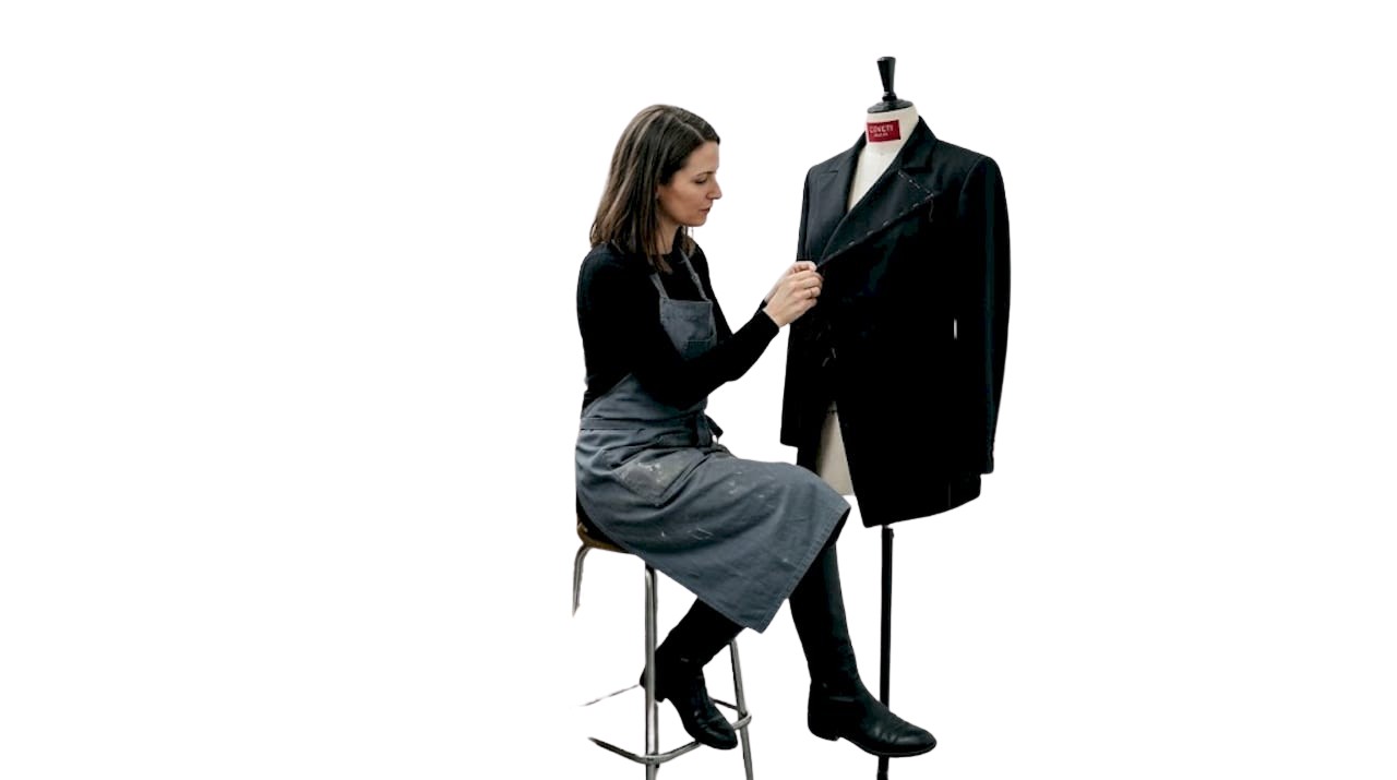 Dans son atelier, un créateur de mode réalise à la main les finitions d’une veste avant-gardiste.