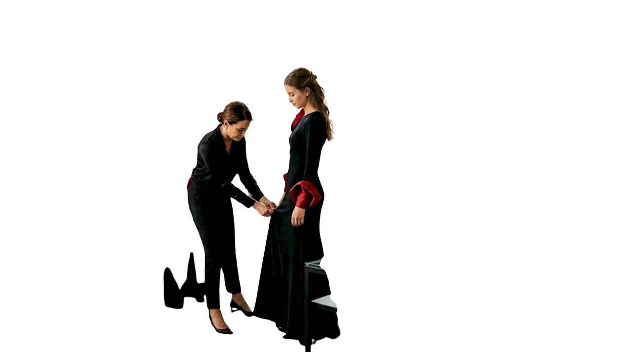 Una stylist sistema con cura un abito da gala all’interno dello showroom.