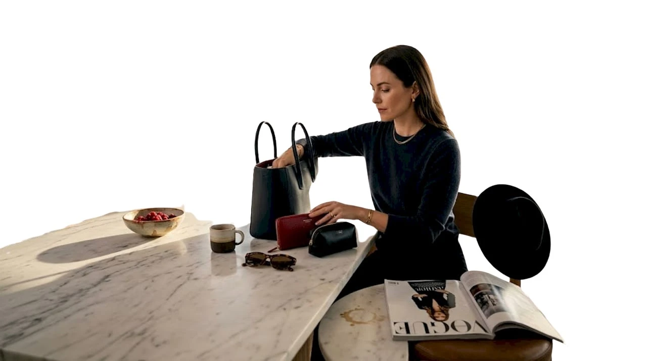 Eine Frau räumt ihre Designer-Handtasche für den Alltag neu ein.