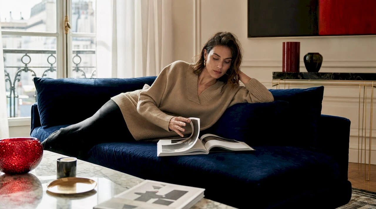 Installée confortablement chez elle, une femme explore les dernières tendances de la mode de luxe sur son ordinateur.