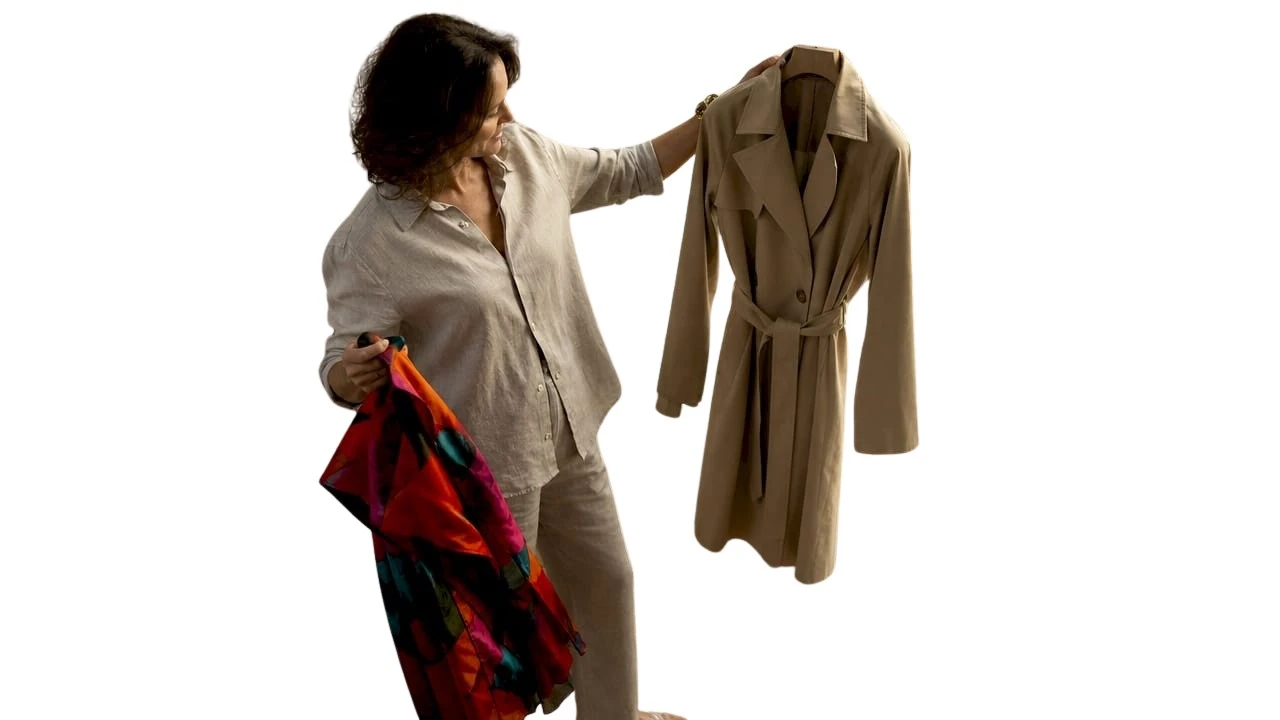 Une femme se tient devant son miroir, hésitant entre une tenue classique et un look plus moderne.
