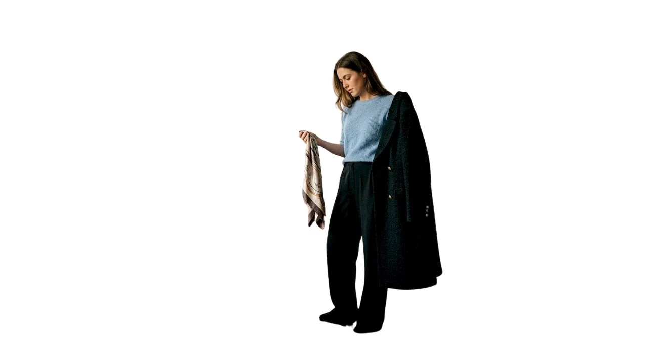 Eine Frau steht in ihrem gemütlichen Schlafzimmer und überlegt, welches Outfit sie heute anziehen soll.