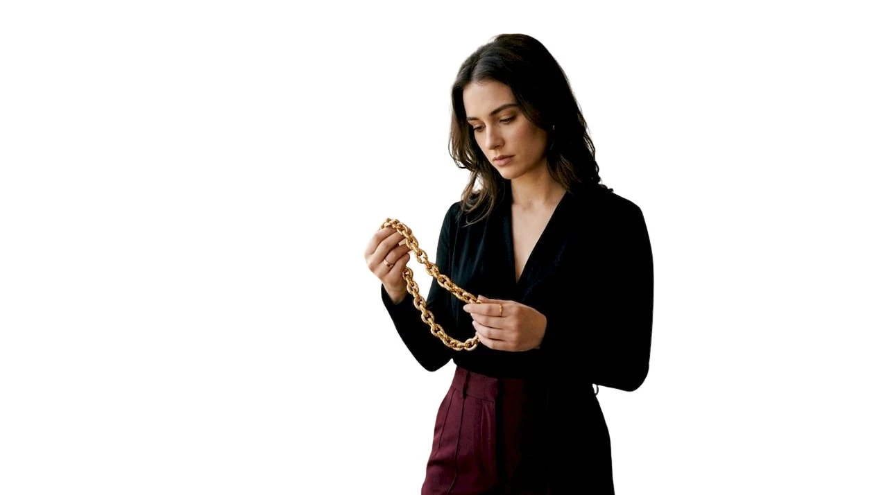 Vrouw bekijkt opvallende, goudkleurige ketting van dichtbij