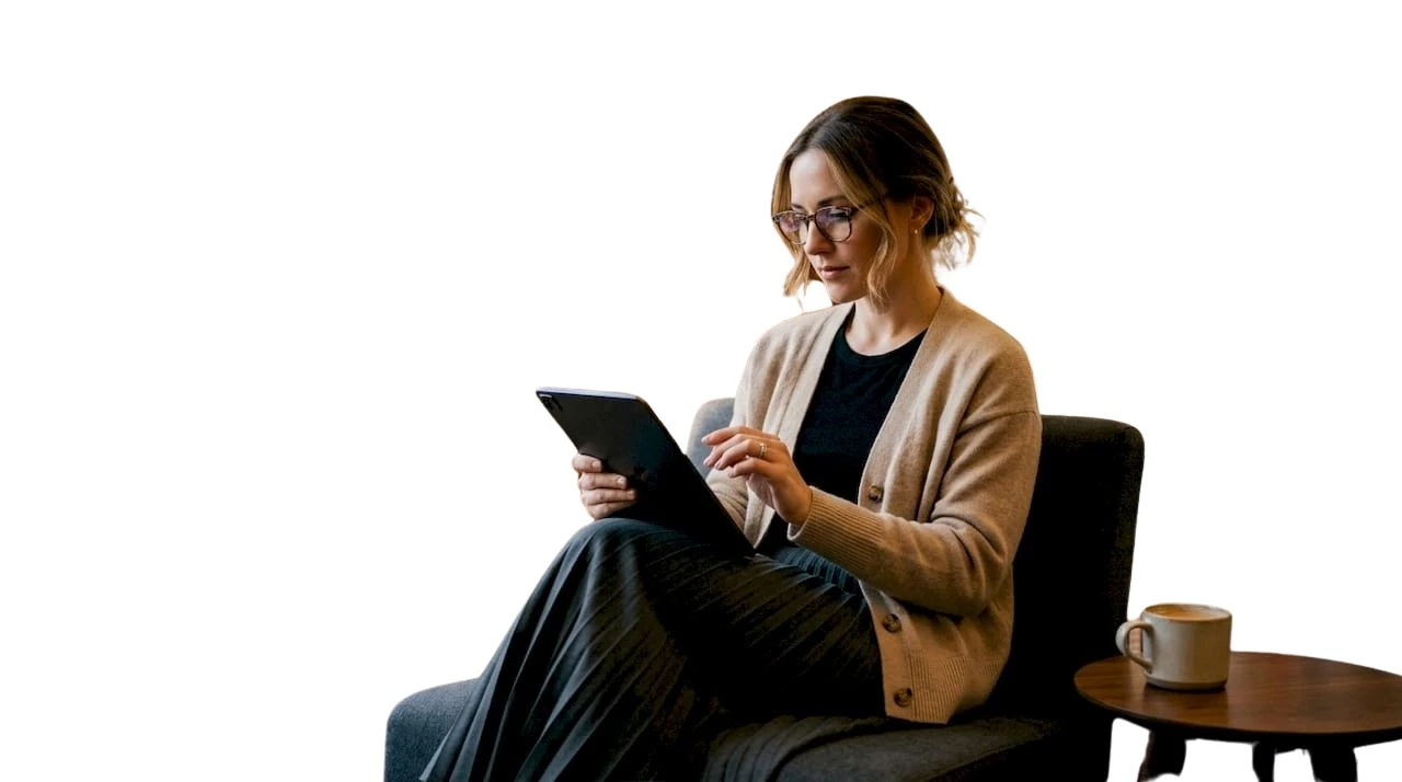Una donna sfoglia le ultime novità di moda di lusso sul tablet, comodamente seduta a casa.