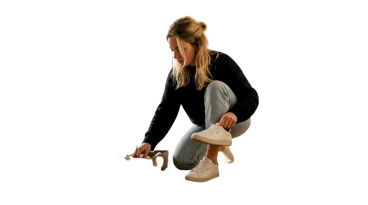 Een vrouw past binnenshuis een paar sneakers om te kijken of ze lekker zitten.