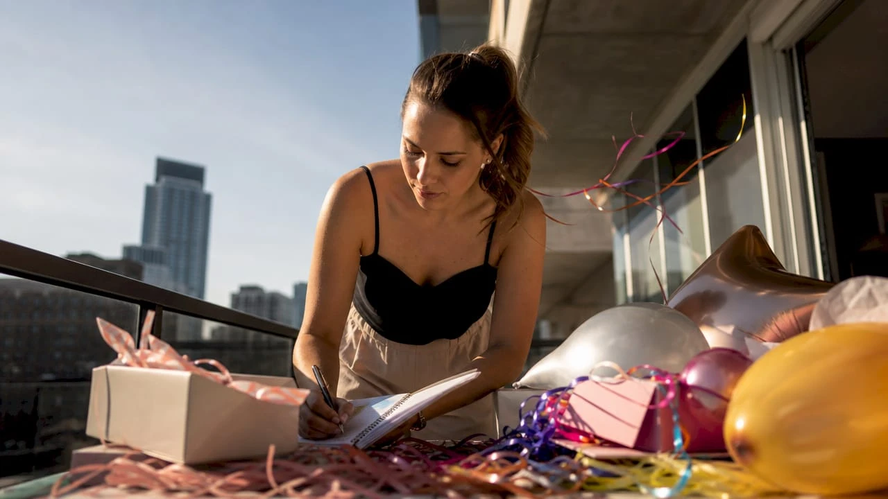 Una mujer revisa y organiza la lista de accesorios para la fiesta sobre la mesa, asegurándose de que todo esté listo para el gran día.